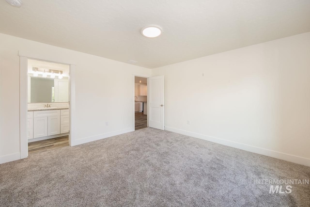 unfurnished bedroom with carpet flooring, ensuite bath, and sink