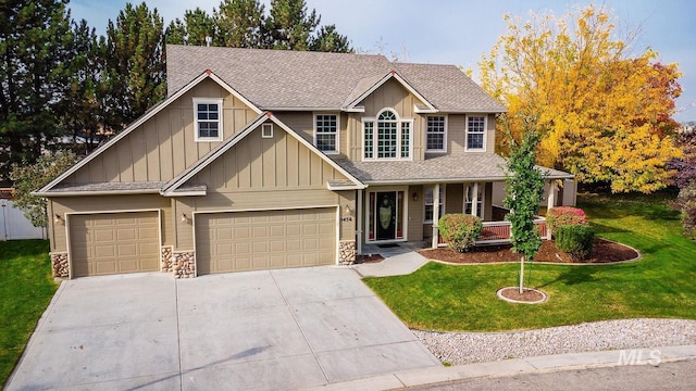 view of front of property featuring stone siding, concrete driveway, board and batten siding, and a front yard