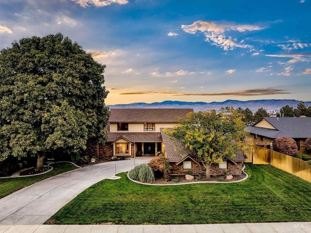 view of front facade with concrete driveway, stone siding, and a mountain view
