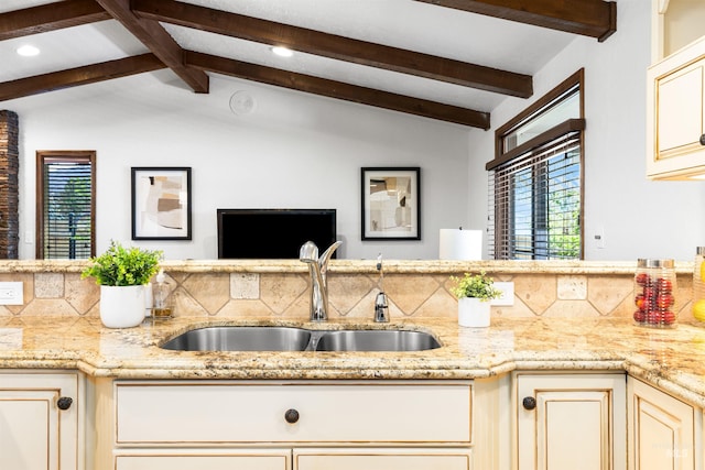 kitchen with a sink, cream cabinetry, healthy amount of natural light, light stone counters, and recessed lighting