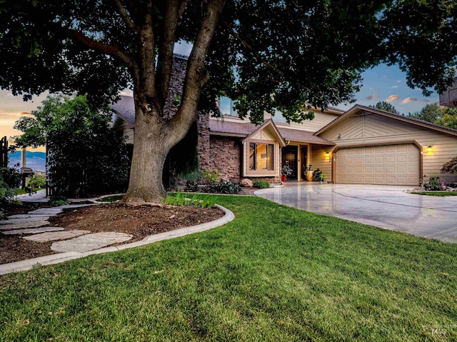 view of front of property featuring a garage, driveway, a front yard, and stone siding