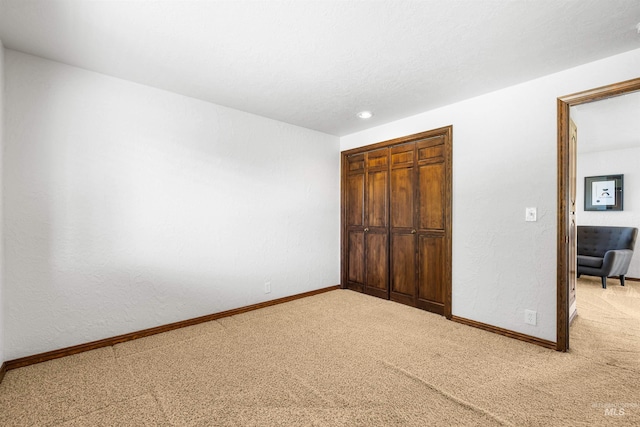 unfurnished bedroom featuring carpet, a closet, baseboards, and recessed lighting