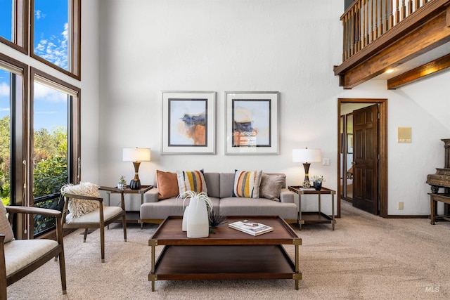 living area featuring light carpet, a towering ceiling, and baseboards