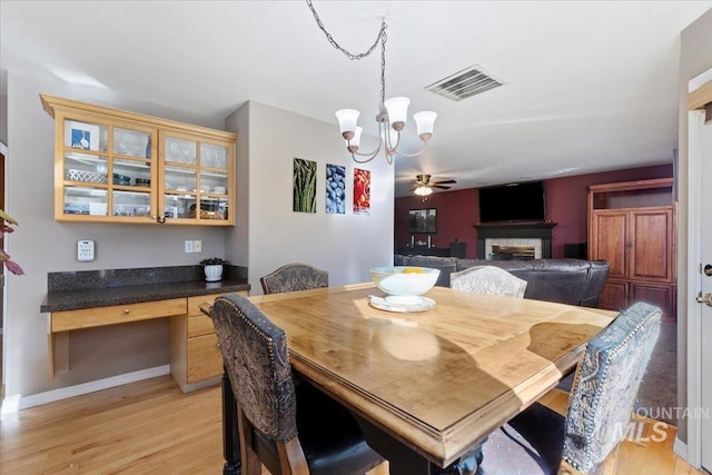 dining area featuring built in desk, light hardwood / wood-style floors, and ceiling fan