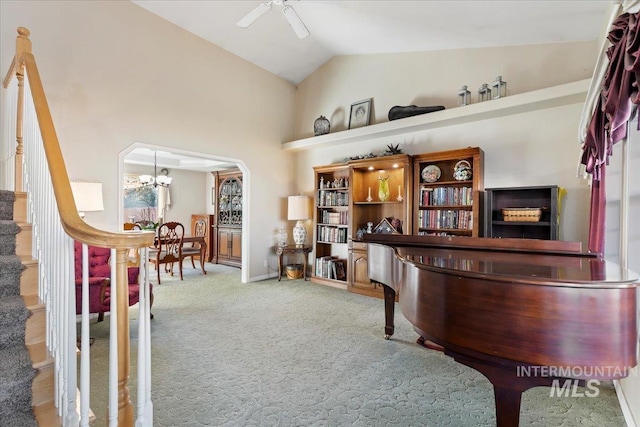 interior space with ceiling fan with notable chandelier, high vaulted ceiling, and carpet