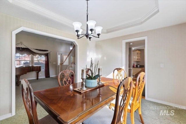 dining space featuring a raised ceiling, ornamental molding, carpet flooring, and a notable chandelier