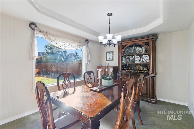 dining room featuring ornamental molding, a notable chandelier, dark carpet, and a tray ceiling