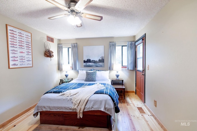 1955 E Parkside Dr, Boise, ID 83712 - bedroom with a textured ceiling, light wood-style floors, multiple windows, baseboards, and a ceiling fan