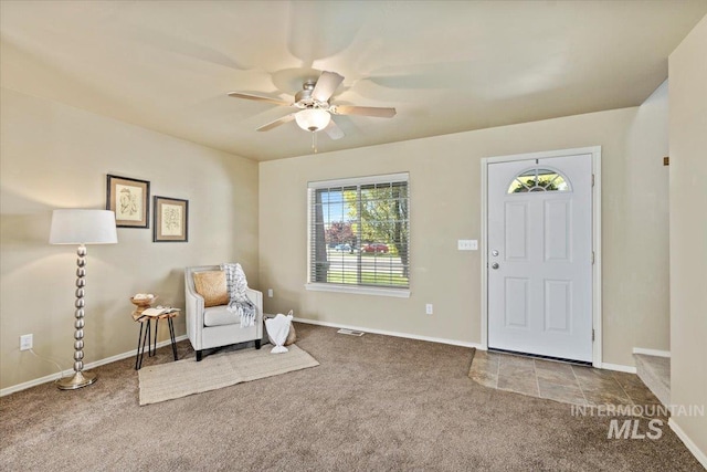 foyer entrance featuring carpet flooring, a ceiling fan, and baseboards
