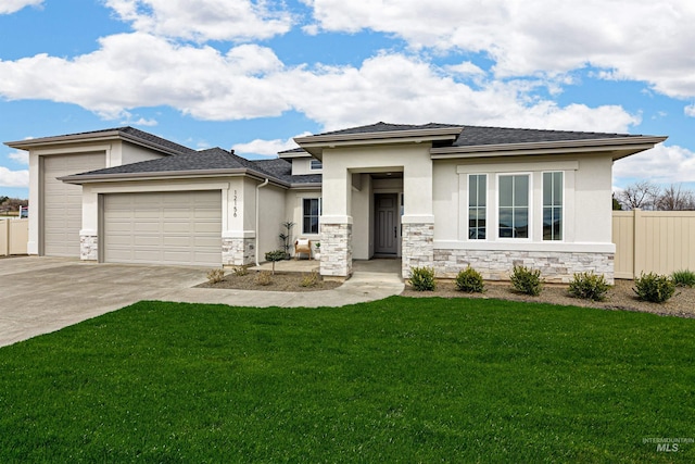 prairie-style home featuring a front yard, fence, an attached garage, stucco siding, and stone siding