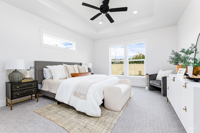 bedroom featuring a raised ceiling, recessed lighting, baseboards, light colored carpet, and ceiling fan