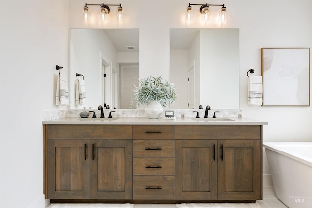 bathroom featuring a sink, a freestanding tub, visible vents, and double vanity