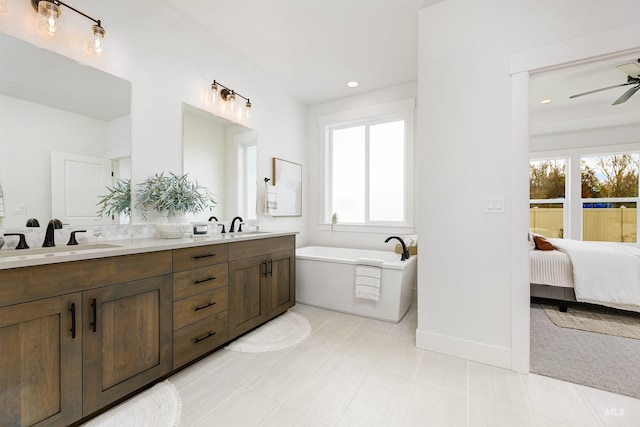 ensuite bathroom featuring a tub, a wealth of natural light, and a sink