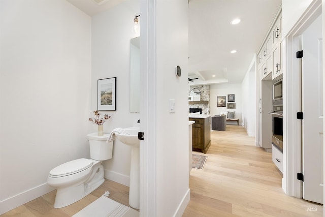 bathroom featuring wood finished floors, baseboards, recessed lighting, toilet, and backsplash