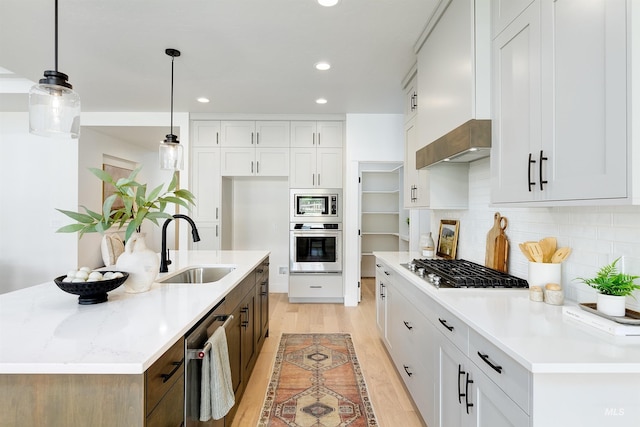 kitchen with a center island with sink, a sink, decorative backsplash, custom range hood, and appliances with stainless steel finishes