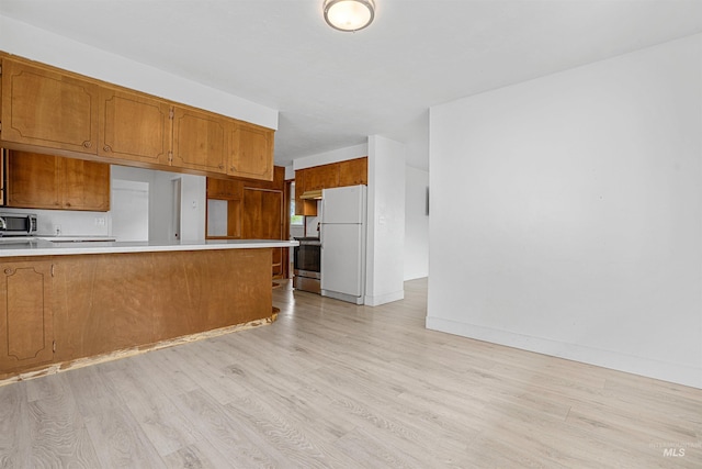 1006 S B St, Rupert, ID 83350 - kitchen featuring stainless steel appliances, light wood-style flooring, light countertops, brown cabinets, and a peninsula