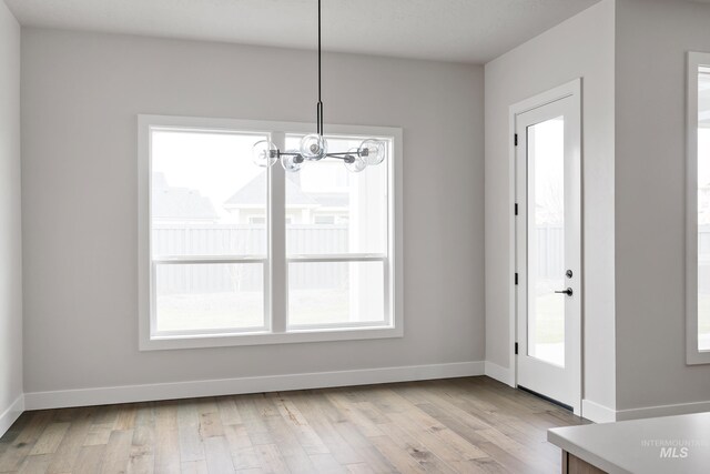 4364 N Madden Way, Meridian, ID 83646 - unfurnished dining area with baseboards, light wood-type flooring, and an inviting chandelier