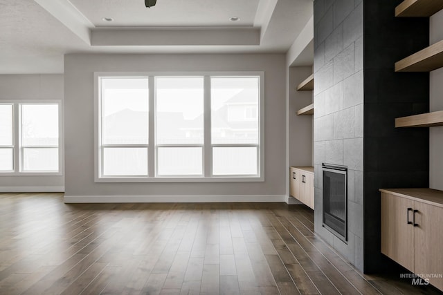 4364 N Madden Way, Meridian, ID 83646 - unfurnished living room with a tray ceiling, baseboards, a tile fireplace, and dark wood-style floors