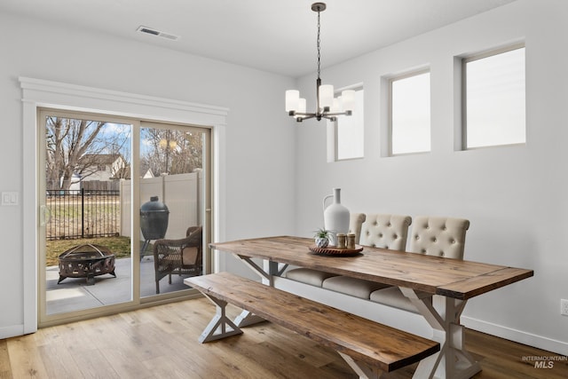 dining area with visible vents, baseboards, an inviting chandelier, and light wood finished floors