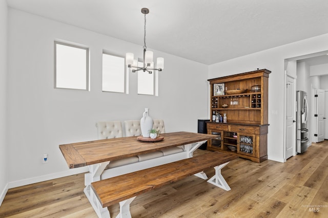 dining area with light wood finished floors, a chandelier, and baseboards