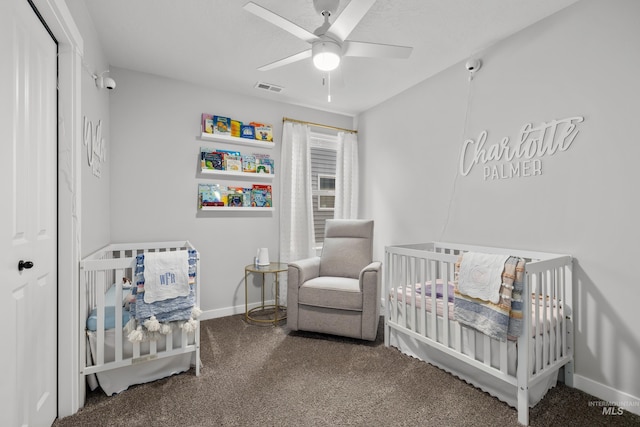 bedroom with visible vents, a crib, ceiling fan, baseboards, and carpet flooring