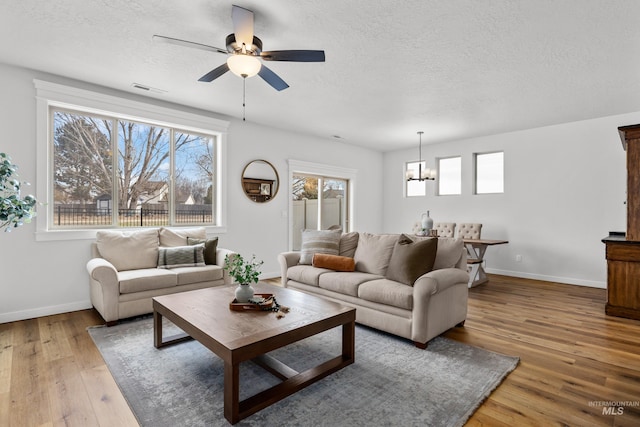 living room featuring plenty of natural light, a textured ceiling, light wood-type flooring, and visible vents