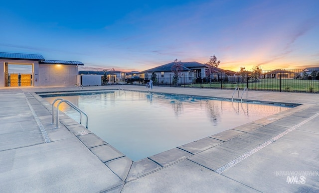 pool at dusk with a patio area, a fenced in pool, and fence