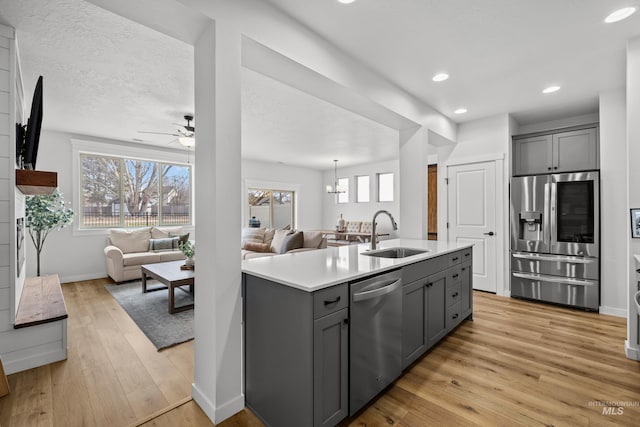 kitchen featuring open floor plan, light countertops, gray cabinets, appliances with stainless steel finishes, and a sink