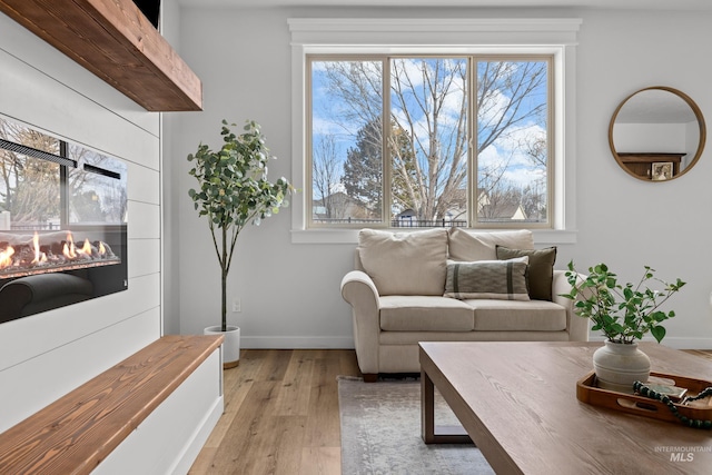 living area featuring light wood-style flooring, a fireplace, and baseboards