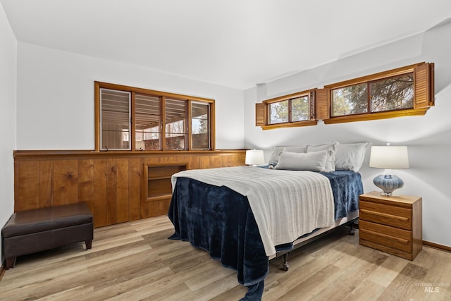 bedroom with light hardwood / wood-style floors and wooden walls