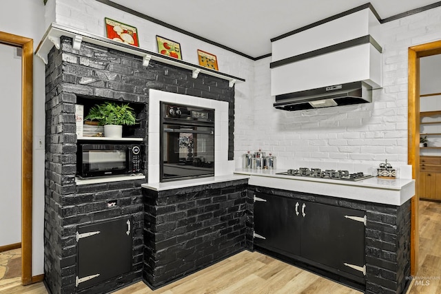 kitchen featuring black appliances, light hardwood / wood-style flooring, and brick wall