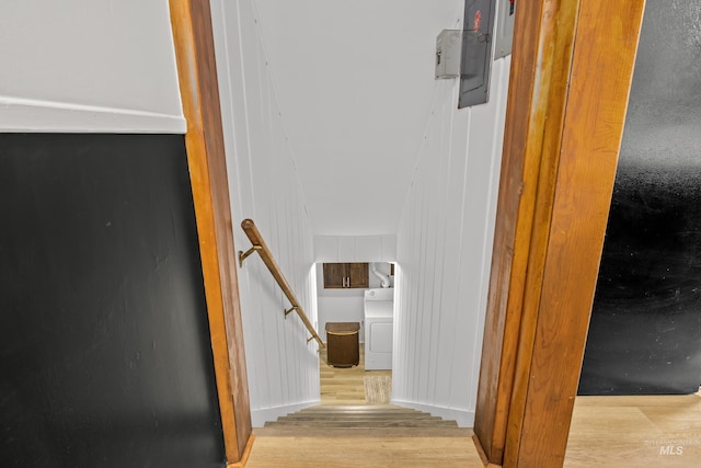 stairs with washer / dryer, wood-type flooring, and wood walls