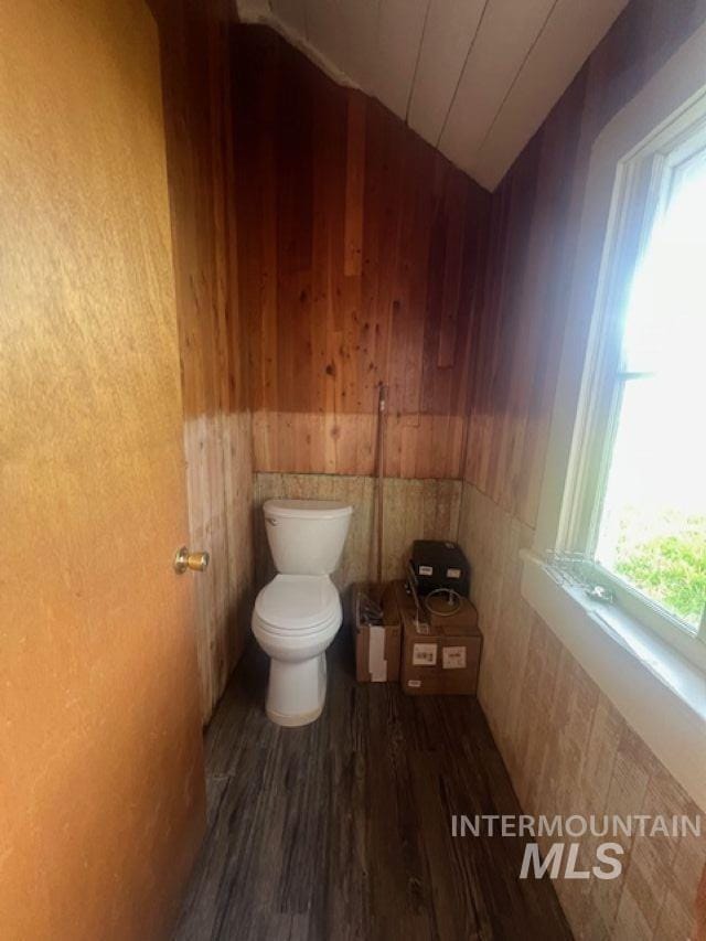 2070 Woodland Rd, Kamiah, ID 83536 - bathroom with vaulted ceiling, wood finished floors, wood walls, toilet, and a wainscoted wall