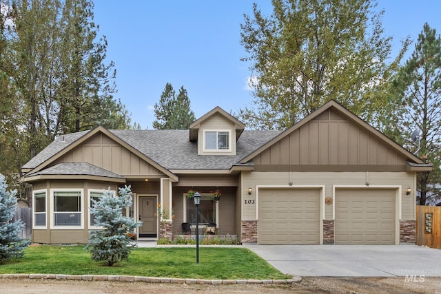 craftsman-style house with a shingled roof, concrete driveway, an attached garage, a front yard, and stone siding