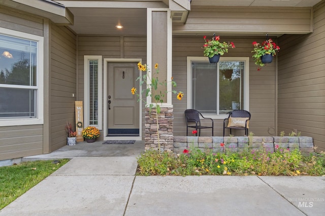 view of exterior entry with stone siding and a porch