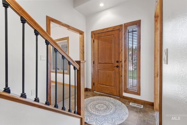 foyer entrance with baseboards, stairs, and visible vents