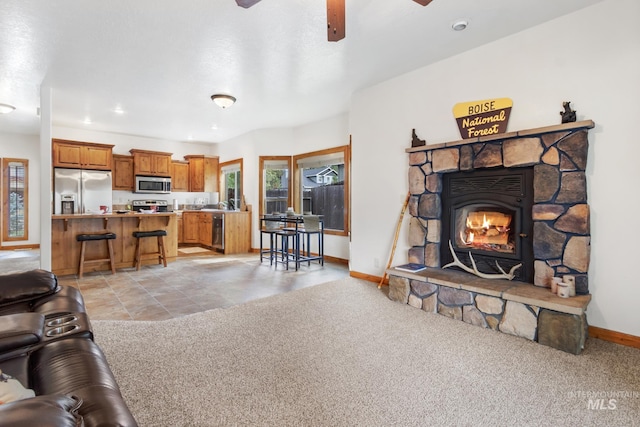 living area with a ceiling fan, light colored carpet, and baseboards