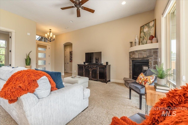 living room with ceiling fan with notable chandelier, light colored carpet, and a fireplace