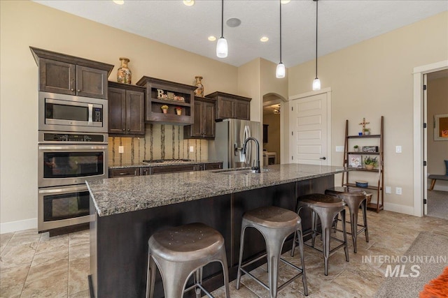 kitchen with dark brown cabinetry, stainless steel appliances, a kitchen breakfast bar, and hanging light fixtures