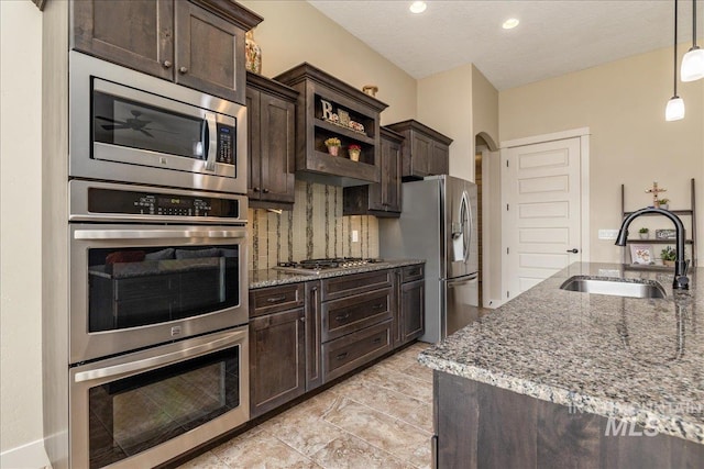 kitchen featuring hanging light fixtures, stainless steel appliances, sink, and dark brown cabinets