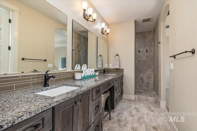 bathroom with vanity, a tile shower, and backsplash