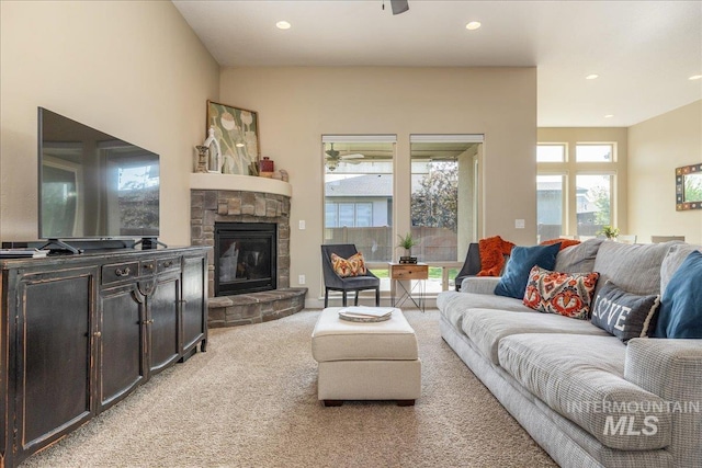 living room featuring a stone fireplace and light colored carpet