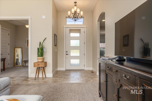 foyer featuring light colored carpet and a chandelier