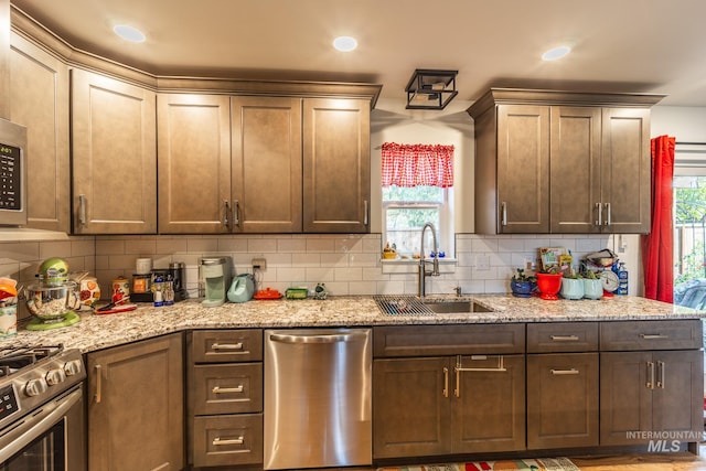 kitchen featuring appliances with stainless steel finishes, sink, tasteful backsplash, and a healthy amount of sunlight