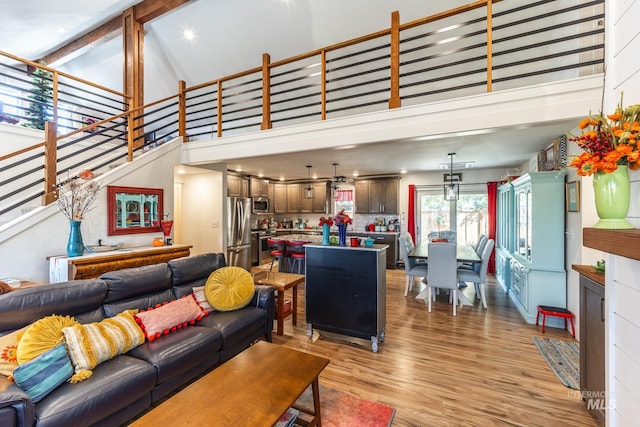 living room with high vaulted ceiling, beamed ceiling, and light hardwood / wood-style flooring