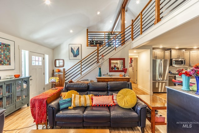 living room featuring beam ceiling, light hardwood / wood-style flooring, and high vaulted ceiling