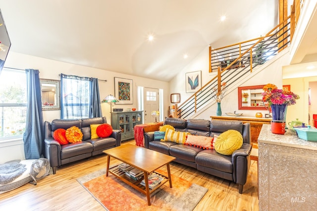 living room featuring light hardwood / wood-style flooring, high vaulted ceiling, and plenty of natural light