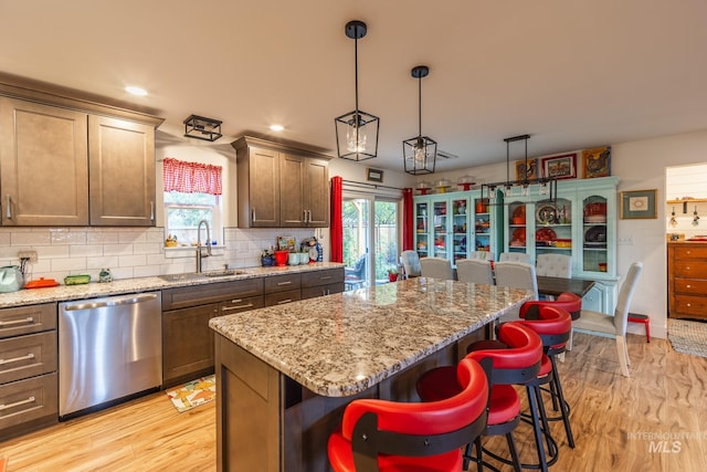 kitchen featuring pendant lighting, stainless steel dishwasher, a healthy amount of sunlight, and a center island