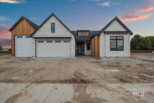 view of front of home with board and batten siding, driveway, stone siding, and a garage