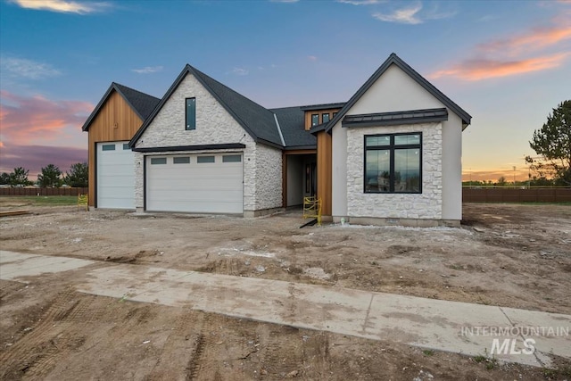view of front of property with fence, stone siding, and a garage